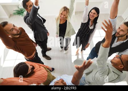 Diverse team of happy young people celebrating success, huddling and having fun in office Stock Photo