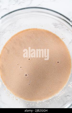 Activating dry yeast in a glass mixing bowl to bake mini Easter bread kulich. Stock Photo