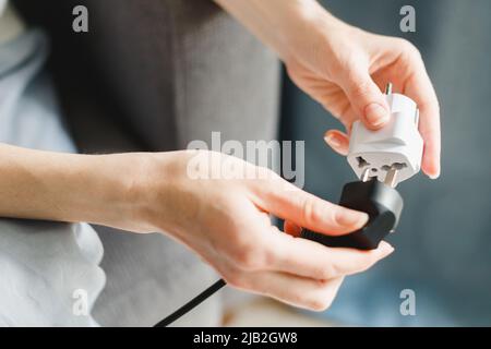Woman applies universal European plug adapter International AU UK US to Euro. Travel adapter electrical plug converter power socket Stock Photo