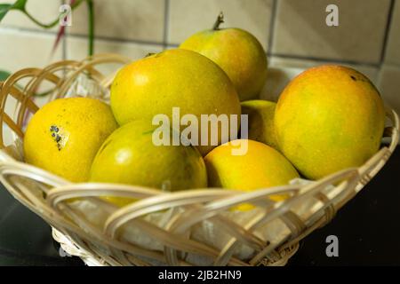 Selective focus on a group of ripe mangoes placed in a fruit basket. Closeup shot. Stock Photo