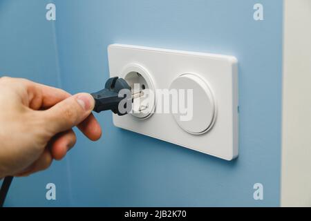 Inserting power cord receptacle in wall outlet Stock Photo