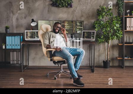 Portrait of attractive cheerful successful skilled guy expert technician sitting in armchair touching specs at workplace workstation indoors Stock Photo