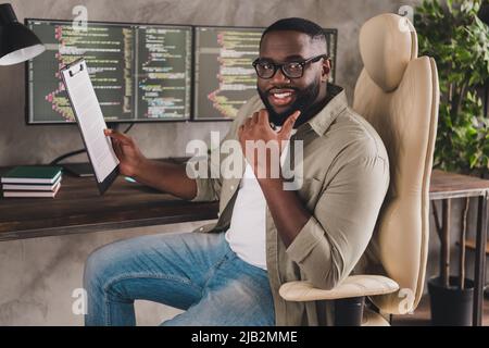 Portrait of attractive cheery skilled guy reading technical document analyzing project startup at work place station indoors Stock Photo