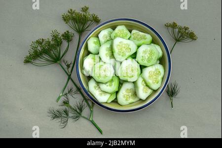 Juicy raw cucumber salad in a plate on a wooden table with dill Stock Photo