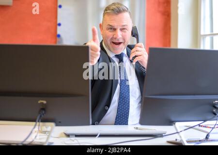 Enthusiastic successful businessman giving a thumbs up with a satisfued smile working in an office Stock Photo