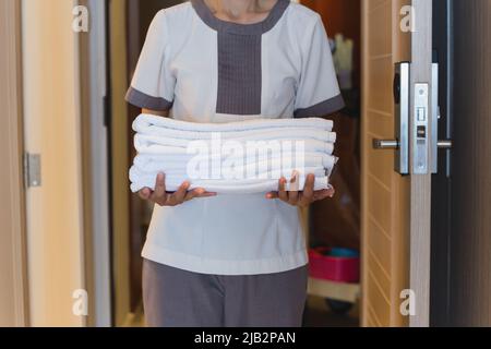 Maid carrying fresh clean towels to hotel room. Stock Photo