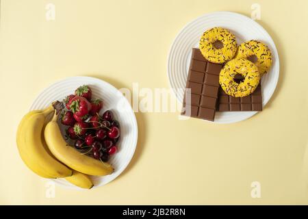healthy and unhealthy food with fruit, berry and sweets on yellow background Stock Photo