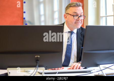 Businessman wearing reading glasses working in office seated at his desk typing on a computer Stock Photo