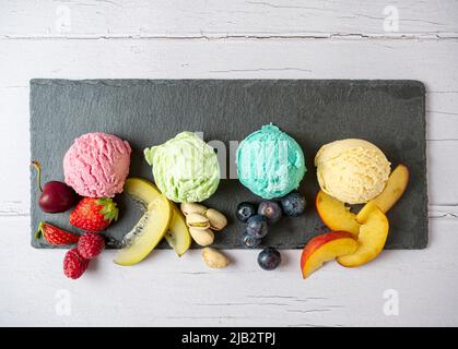 Set of ice cream scoops of different colors and flavours with berries, nuts and fruits decoration isolated on white background Stock Photo