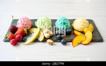 Set of ice cream scoops of different colors and flavours with berries, nuts and fruits decoration isolated on white background Stock Photo