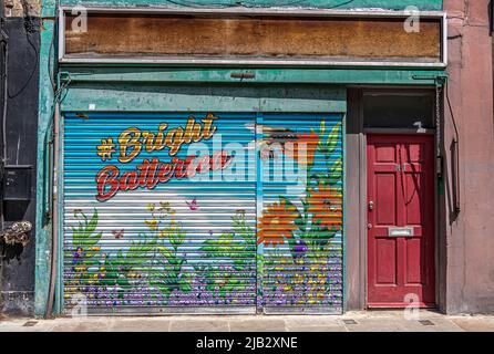 A colourful painted metal roller shutter on a disused shop , painted with the hash tag Bright Battersea on  Battersea  High Street , London, SW11 Stock Photo