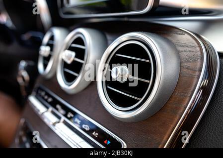 The interior of a modern passenger car with three vents visible and air conditioning control. Stock Photo