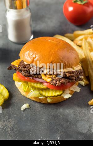 Homemade Cheese Smash Burger with Fries Pickles and Tomatoes Stock Photo