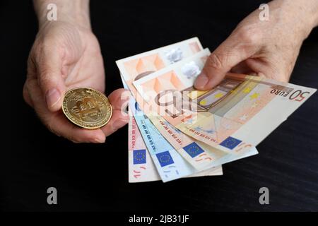 Bitcoin and euro banknotes in wrinkled hands of elderly woman, concept of retirement savings. Electronic decentralized money, crypto currency Stock Photo