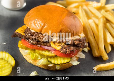Homemade Cheese Smash Burger with Fries Pickles and Tomatoes Stock Photo