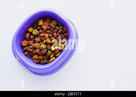 top view of purple plastic bowl with dry dog food isolated on white Stock Photo