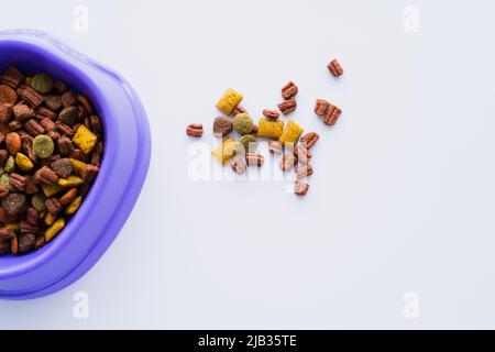 top view of purple plastic bowl with dry cat food isolated on white Stock Photo