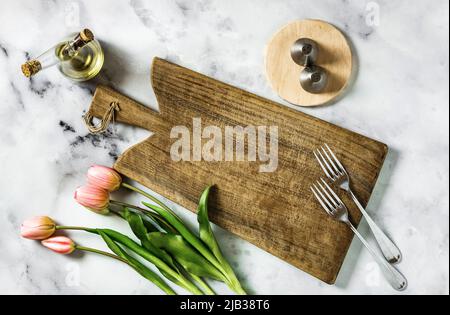 empty cutting board on marble table and tulips. holiday background Stock Photo
