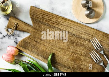 empty cutting board on marble table and tulips. holiday background Stock Photo