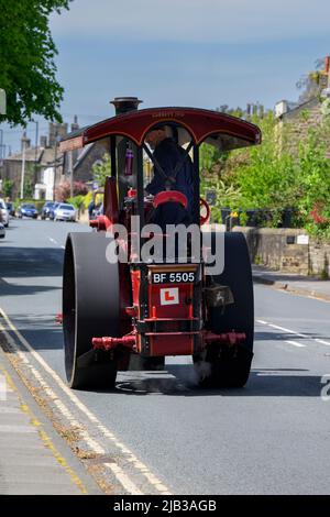 Vintage restored heavy old-fashioned red steam-powered vehicle (black chimney, L-plate, driver) - Burley-in-Wharfedale, West Yorkshire, England, UK. Stock Photo