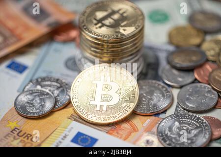 Piled up bitcoin coins on top of dollar and euro banknotes and coins. Crypto currency with paper money from USA and Europe. Blockchain technology exch Stock Photo