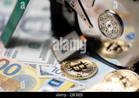 Bitcoin reflecting on hard drive platter next to CPU and on top of euro and dollar banknotes. Cryptocurrency mining concept, blockchain technology. Stock Photo