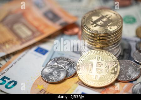 Piled up bitcoin coins on top of dollar and euro banknotes and coins. Crypto currency with paper money from USA and Europe. Blockchain technology exch Stock Photo