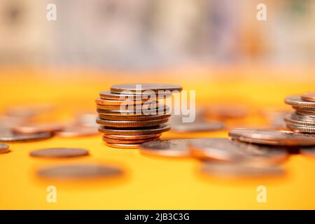 US dollar coins on orange background. Half dollar coins piled up with pennies and quarters. Dollar currency stacked and piled up Stock Photo