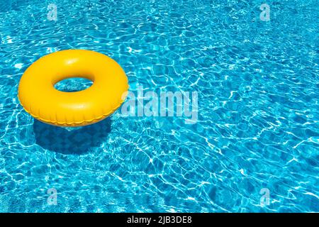 Yellow ring floating in blue swimming pool. Inflatable ring, rest concept Stock Photo