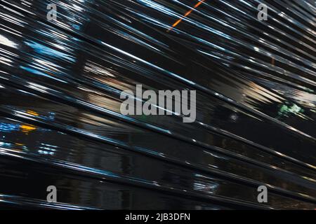 Black plastic wrap background. Crumpled wrinkled plastic cellophane. Reflecting light and shadow on creases and folds in plastic surface. Texture Stock Photo