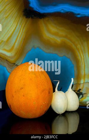 Ripe melon and two small decorative pumpkins on an abstract background Stock Photo