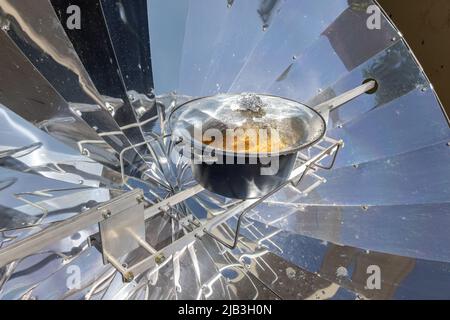 Cooking with sun energy, parabolic solar oven in the middle of cooking a dish thanks to solar energy Stock Photo