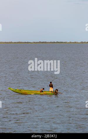 A small local fishing boat with two young boy fishermen in Tonle Sap lake on the Mekong River system, Siem Riep / Pursat Province, north-west Cambodia Stock Photo