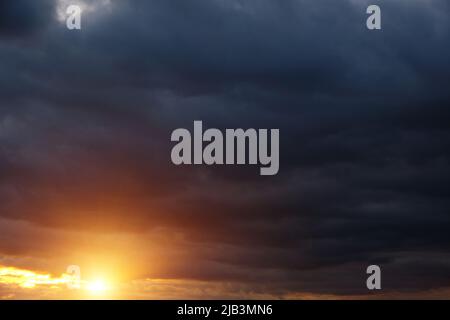 Thunderclouds with breaking rays sun at sunset Stock Photo