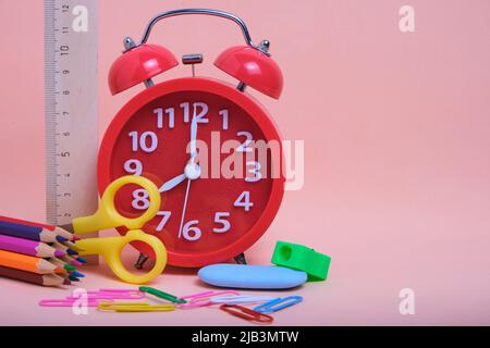Red alarm clock,school supplies and stationery on a pink background Stock Photo