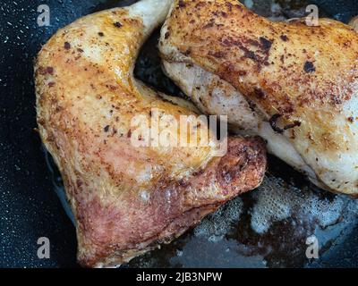 Two chicken legs are fried in a pan in a large amount of oil. Close-up. Stock Photo