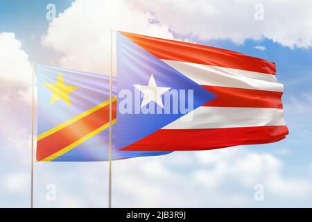 Sunny blue sky and flags of puerto rico and dr congo Stock Photo