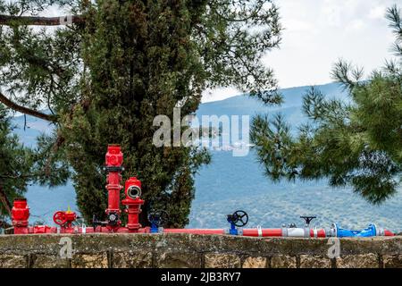 Industrial water pipes with valves and hose connections are located above the ground in the park. Close-up. Stock Photo