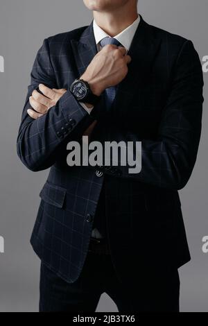 A man in a suit adjusts his tie. Vertical photo Stock Photo