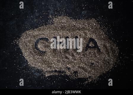 Top view of organic chia seeds in a pile on dark moody background word chia spelled in pile of oats. Stock Photo