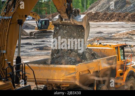 Excavator bucket - loading soil to dump truck, close up photo Stock Photo