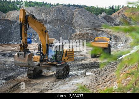 Big dump truck waits for loading by excavator - ground preparing for concrete foundations on the site of a new building Stock Photo