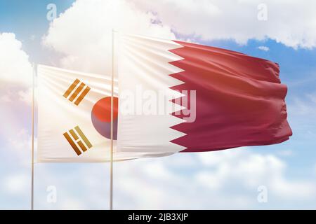 Sunny blue sky and flags of qatar and south korea Stock Photo
