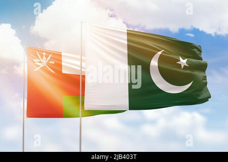 Pakistan Sunny R Oman and Pakistan flag waving together in the wind on blue sky, two ...