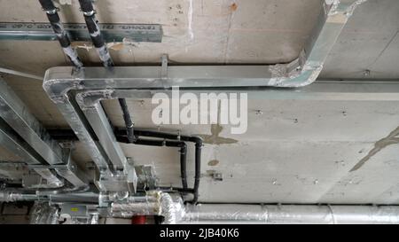 Ceiling in a new apartment with a system of ventilation pipes and wires. Ventilation system in a modern residential apartment during the construction Stock Photo