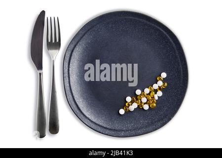 Food supplements and minerals in the form of tablets and pills on a dark plate with cutlery. Fortification of the diet Stock Photo