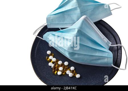 Medical mask, zinc tablets and vitamin d3 pills on a plate with cutlery isolated on white background Stock Photo