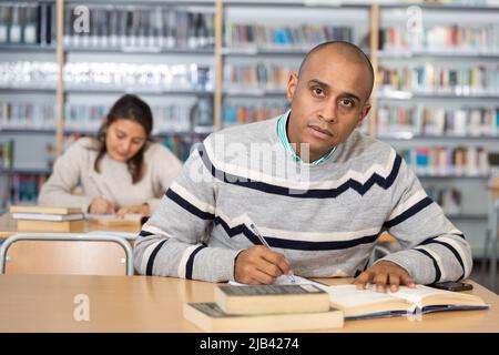 Young adult man studying in public library Stock Photo