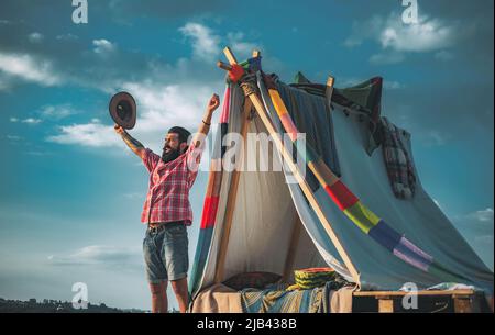 Handsome bearded man inside camping tent. Camping. Go Ape Adventure. Travel homemade tent. Camping outdoor back to nature. Traveling and Camping with Stock Photo