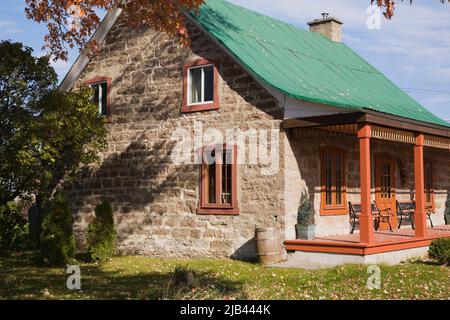 Old circa 1850 Canadiana cottage style cut stone home with green sheet metal roof in autumn. Stock Photo